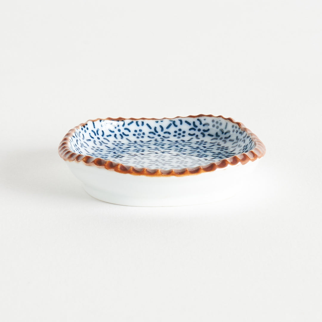 A round plate featuring a blue dotted geometric pattern with a textured brown rim.