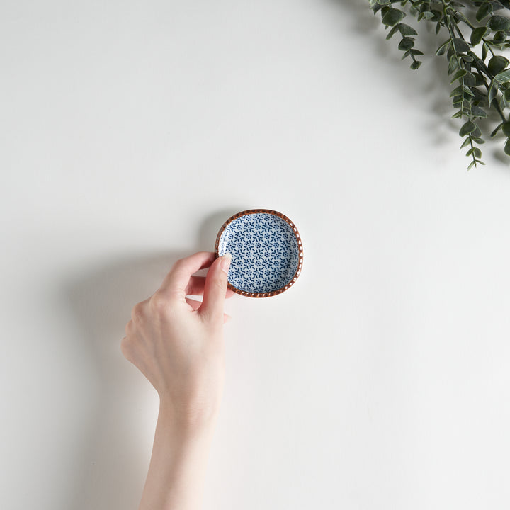 A round plate featuring a blue dotted geometric pattern with a textured brown rim.