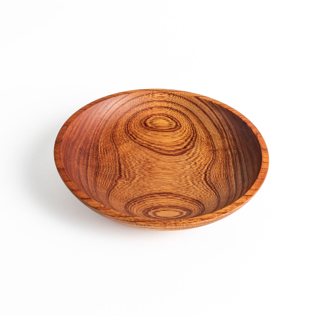 A Zelkova wood salad plate viewed from the side, showcasing its deep curves and beautiful wood texture.