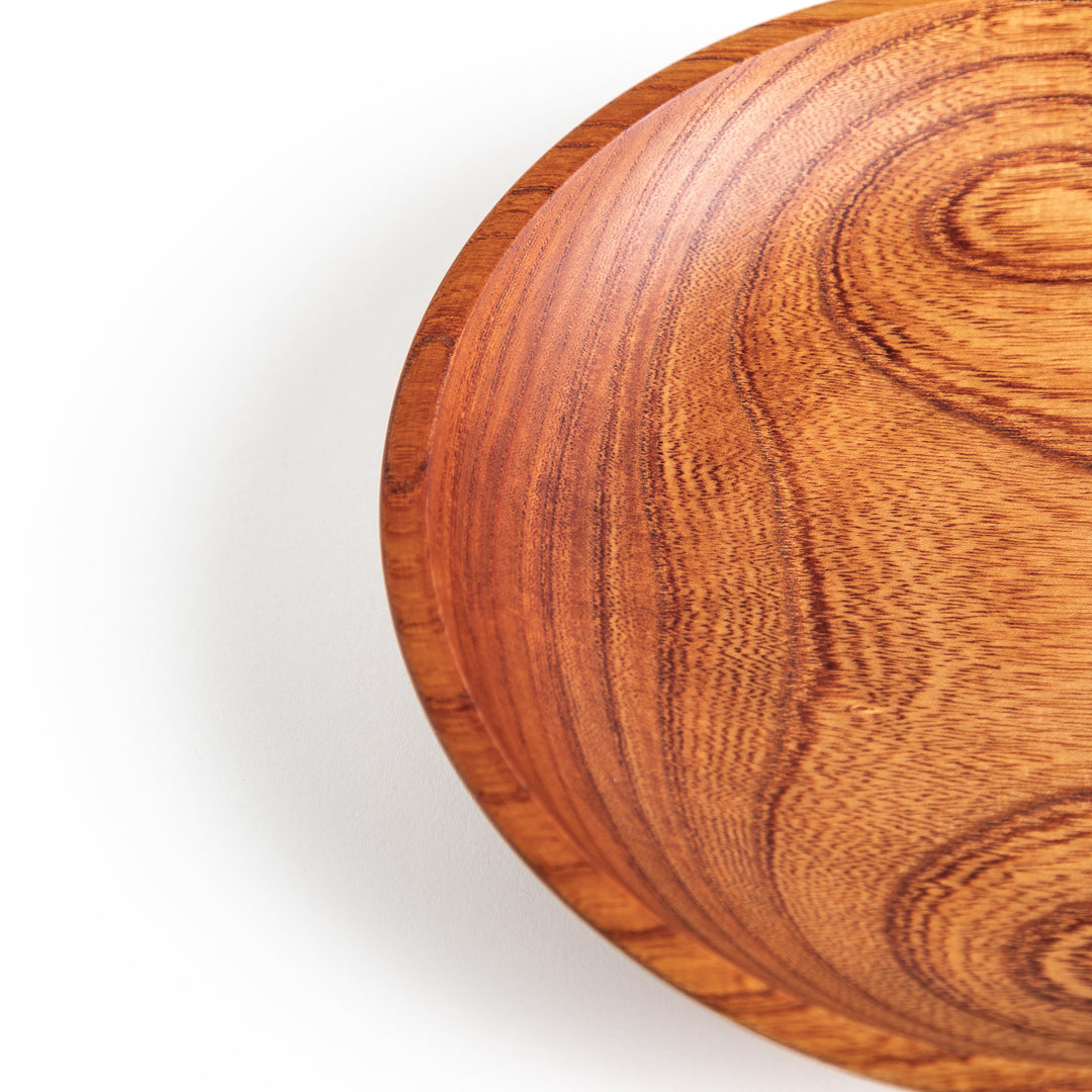 A detailed close-up of the top view of a Zelkova wood salad plate, emphasizing the concentric wood grain design.