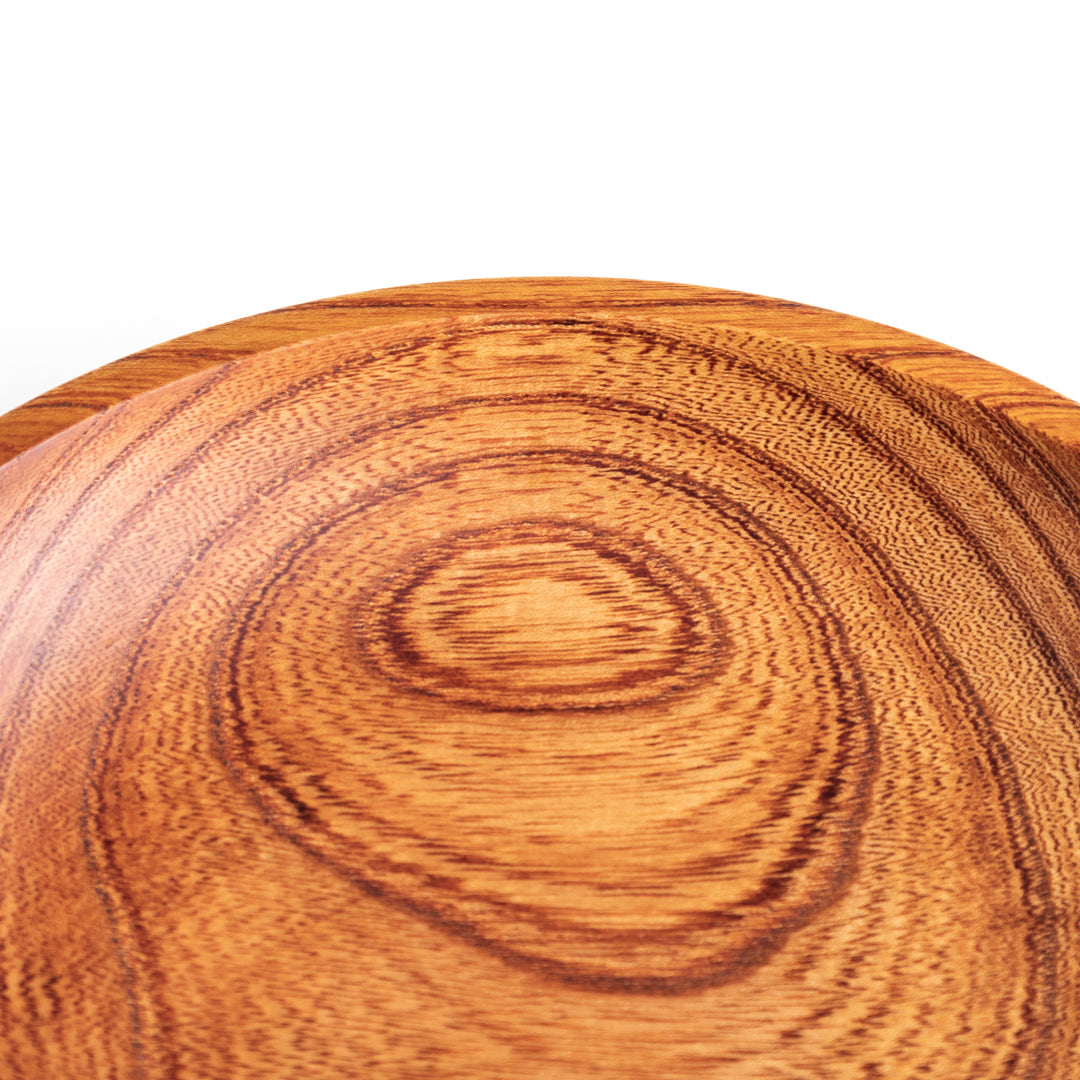 Close-up of the edge of a Zelkova wood salad plate, highlighting the smooth surface and unique swirling grain pattern.