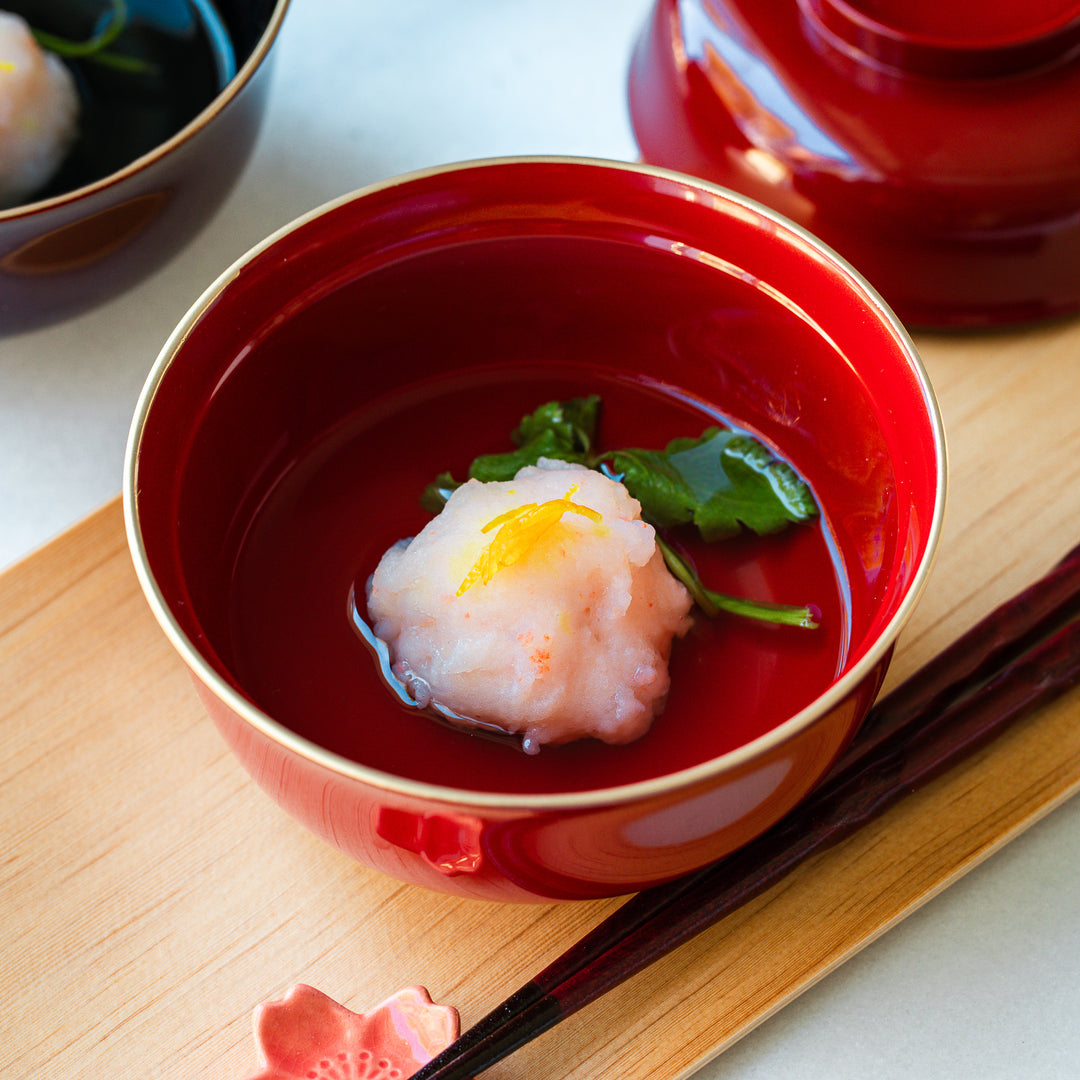 A bowl of Ebi Shinjo, a Japanese dish with shrimp and vegetables, served in a traditional red bowl with a touch of citrus zest, perfect for a refined meal.