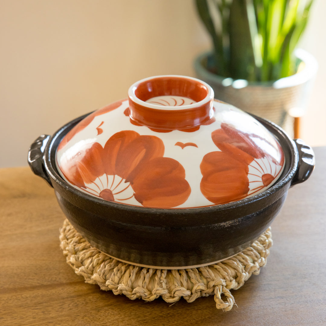 A 8-inch donabe with a vibrant black floral pattern lid and black pot.