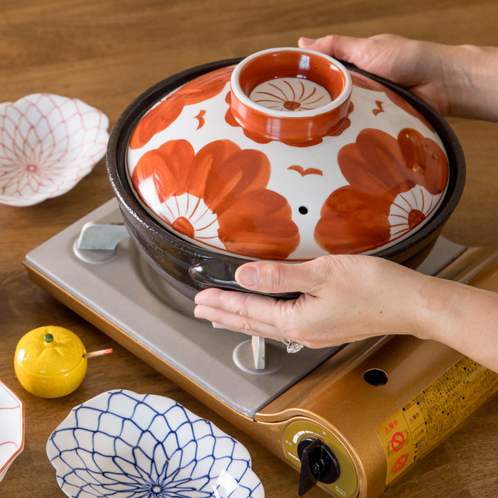 A 8-inch donabe with a vibrant black floral pattern lid and black pot.