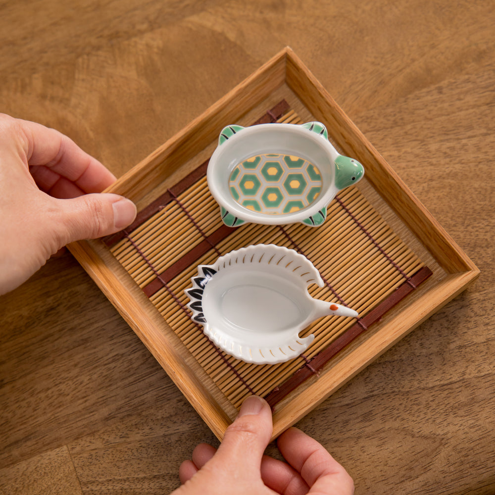 A small round plate with a traditional Japanese design depicting a landscape and floral elements.