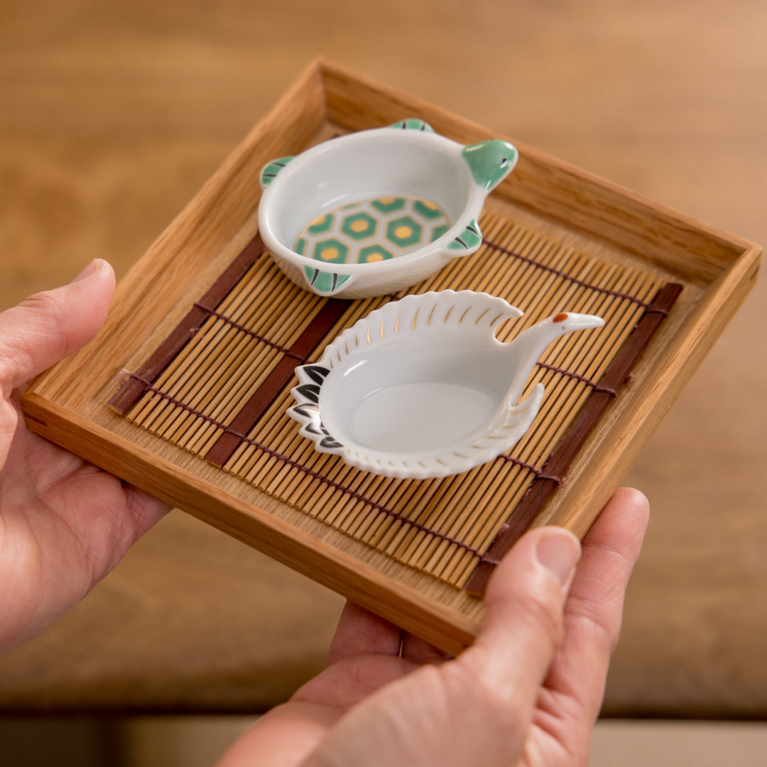 A small round plate with a traditional Japanese design depicting a landscape and floral elements.