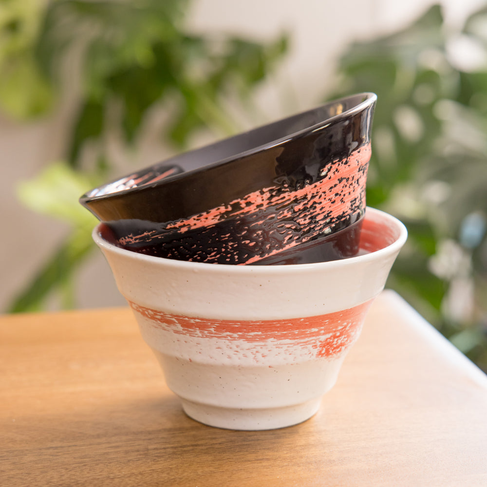 A red ramen bowl with black horizontal lines engraved around its exterior.