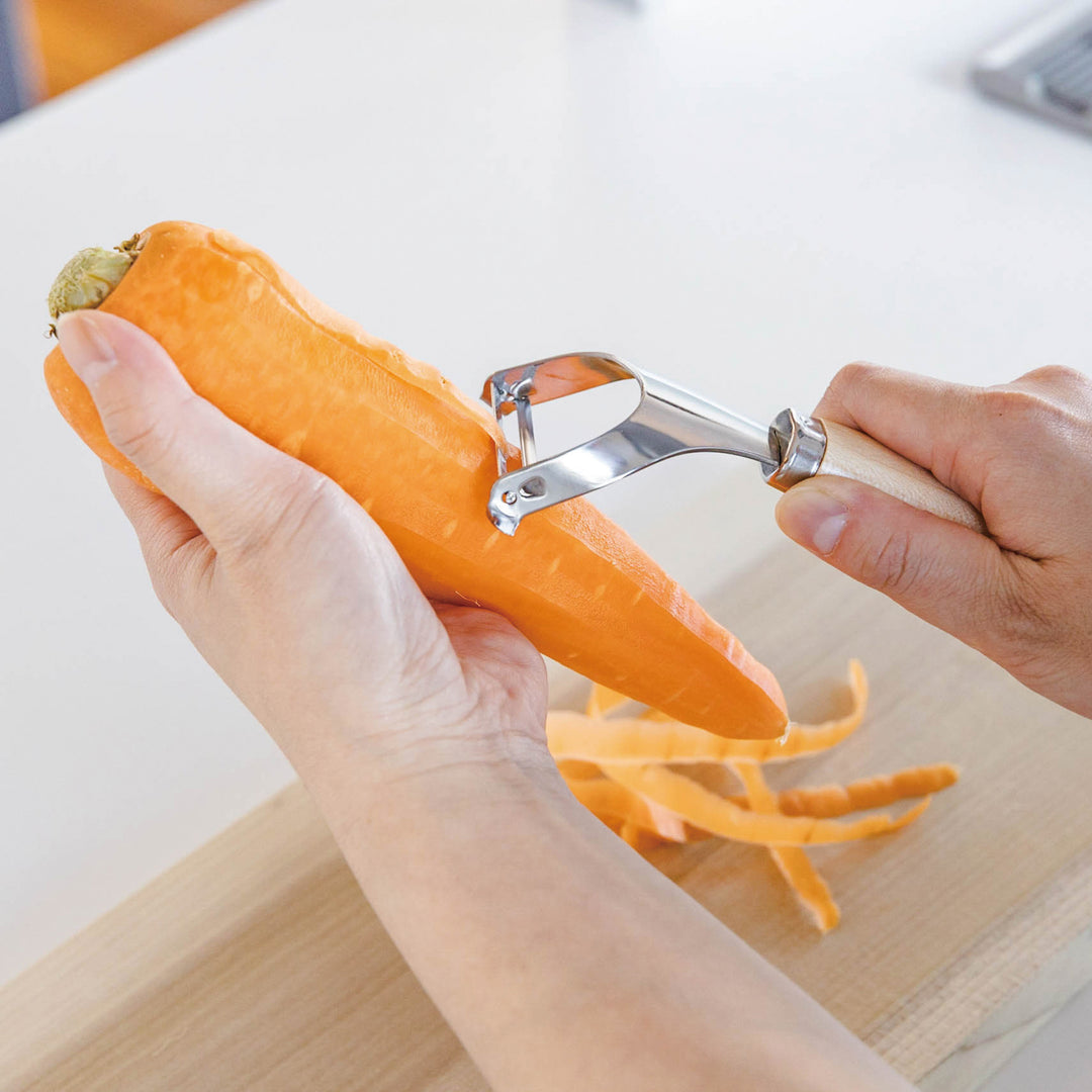 Japanese Wood Handle Peeler, a functional kitchenware with a stainless steel blade and ergonomic wooden handle, ideal for effortless vegetable peeling.