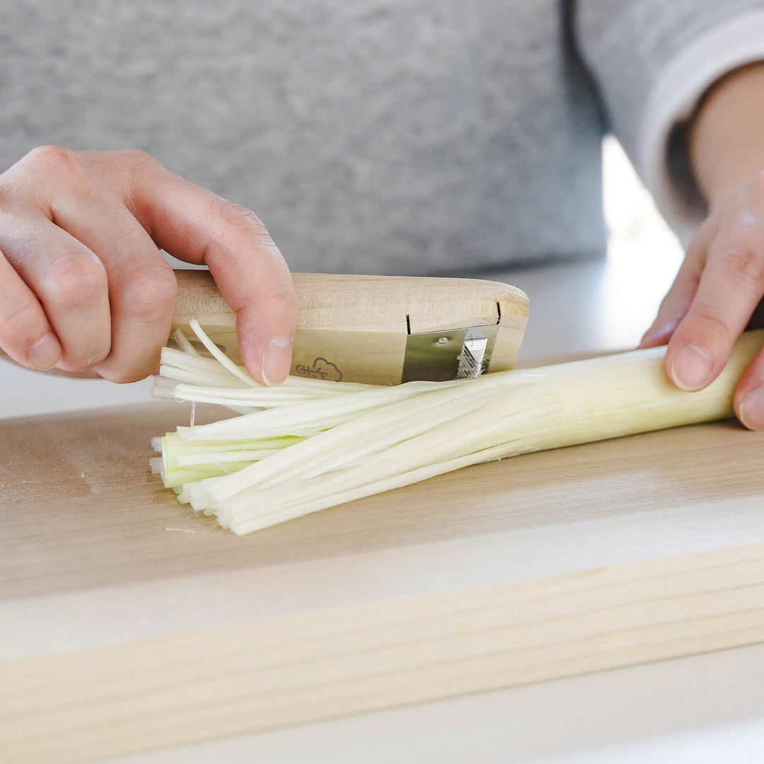 Tokyo Negi Shredder, a kitchenware tool with a wooden body and sharp stainless steel blade, used to finely shred negi (Japanese leeks) effortlessly.