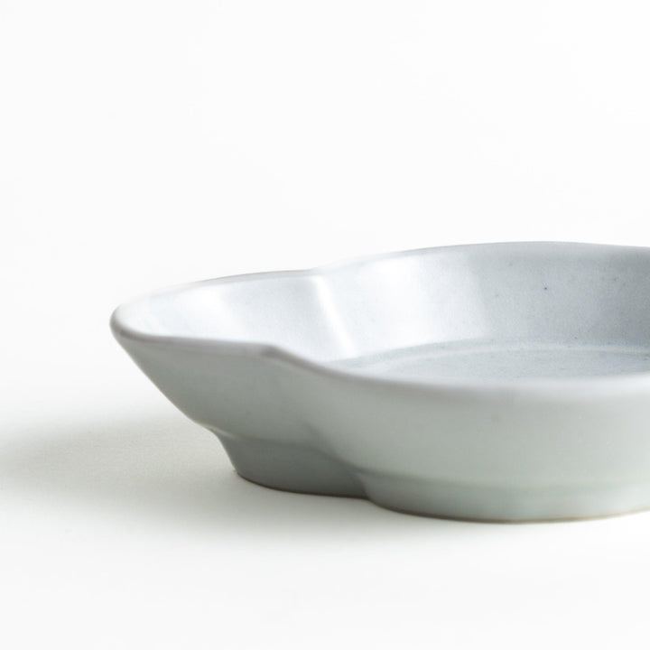 A small, white, quince-shaped ceramic plate with a smooth finish.