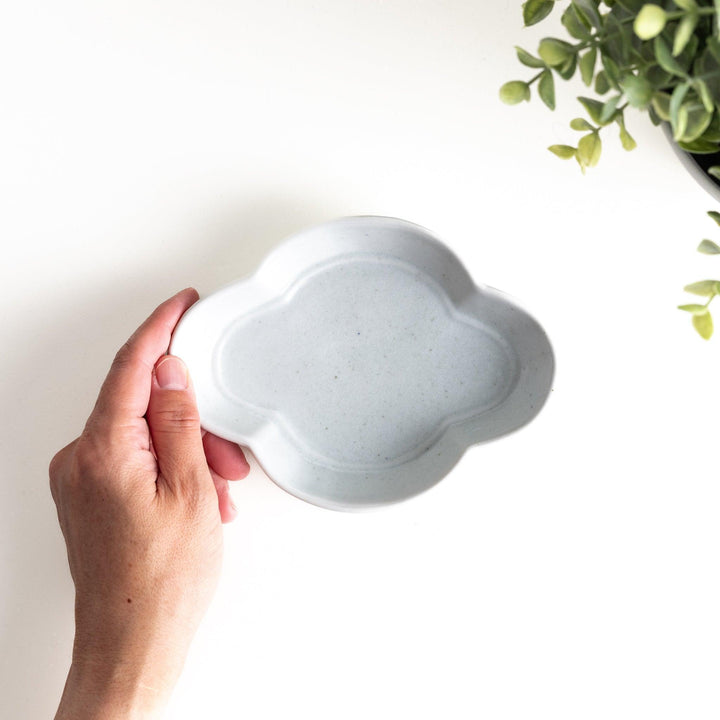 A small, white, quince-shaped ceramic plate with a smooth finish.