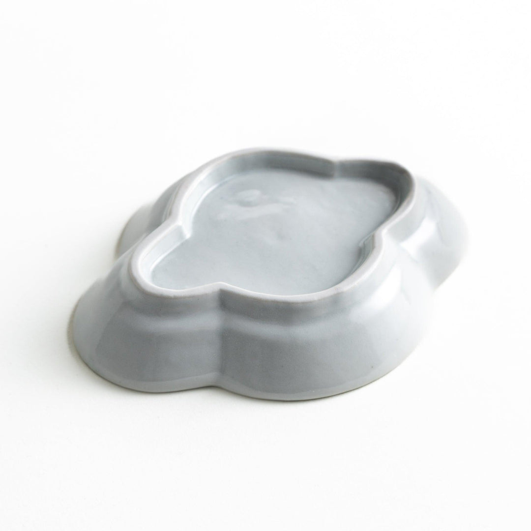 A small, white, quince-shaped ceramic plate with a smooth finish.