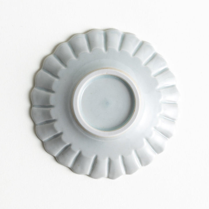 A small white ceramic plate with a fluted edge, featuring a clean, simple design.