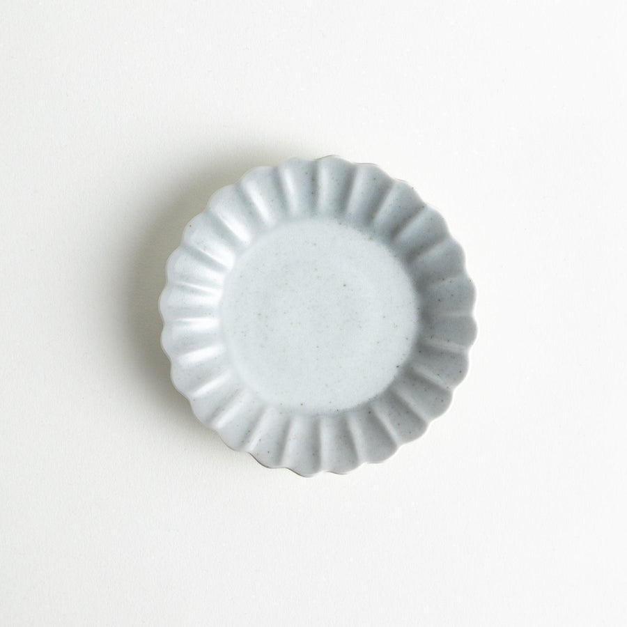 A small white ceramic plate with a fluted edge, featuring a clean, simple design.