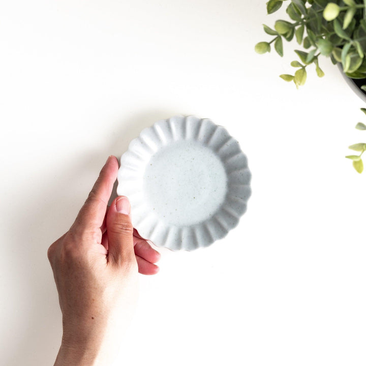 A small white ceramic plate with a fluted edge, featuring a clean, simple design.