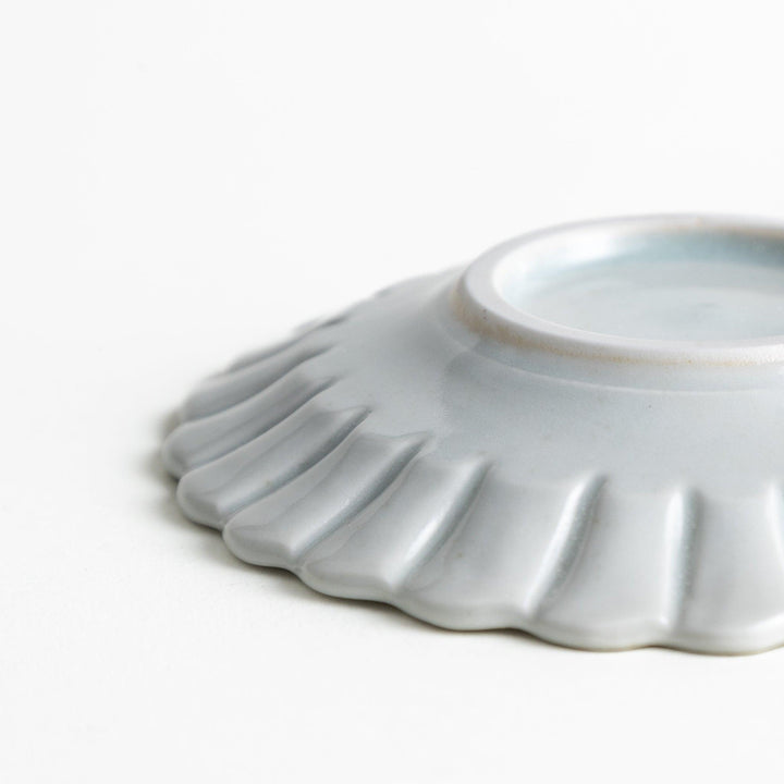 A small white ceramic plate with a fluted edge, featuring a clean, simple design.