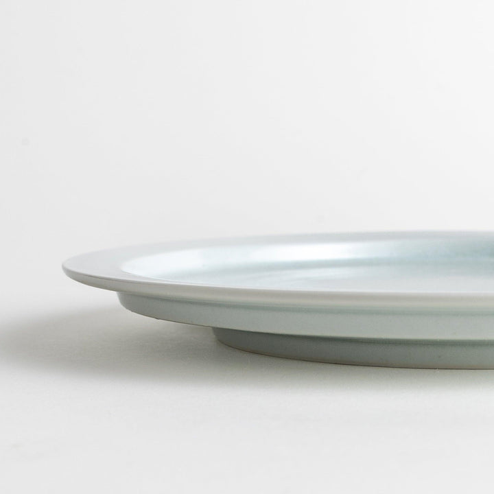 A large round ceramic plate with a clean, minimalist design and a slightly raised edge.