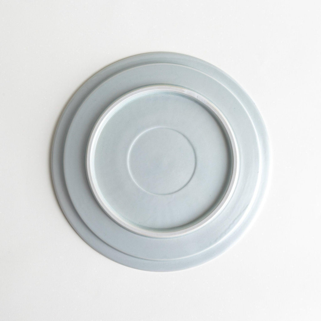 A large round ceramic plate with a clean, minimalist design and a slightly raised edge.