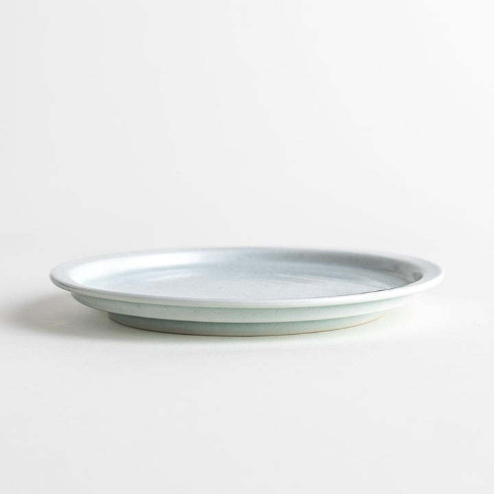 A small, simple round ceramic plate with a minimalist white design.