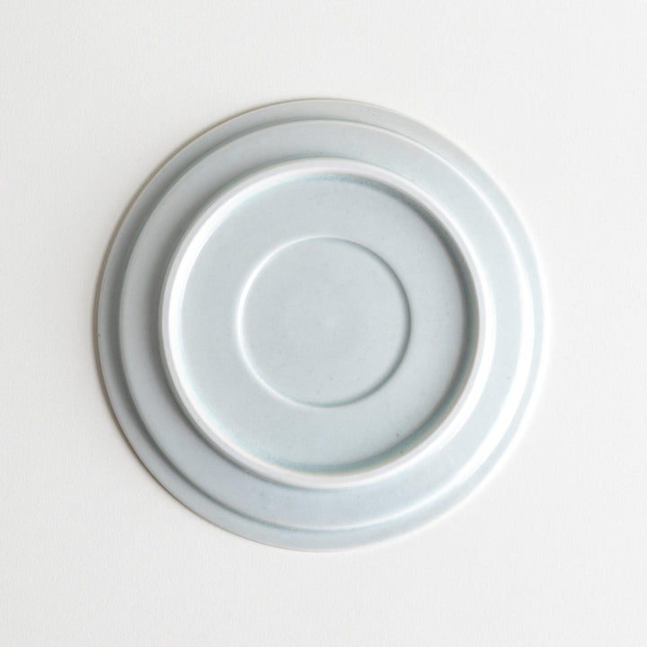 A small, simple round ceramic plate with a minimalist white design.