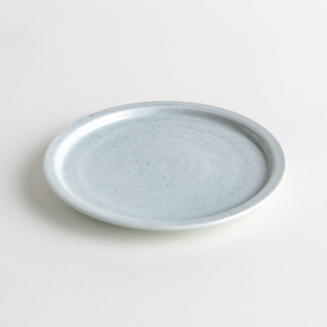 A small, simple round ceramic plate with a minimalist white design.