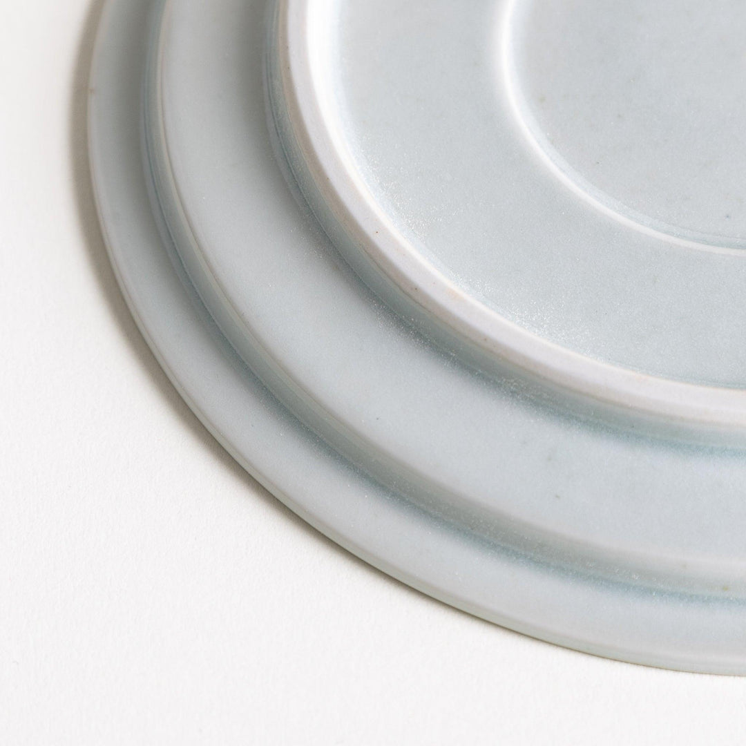 A small, simple round ceramic plate with a minimalist white design.