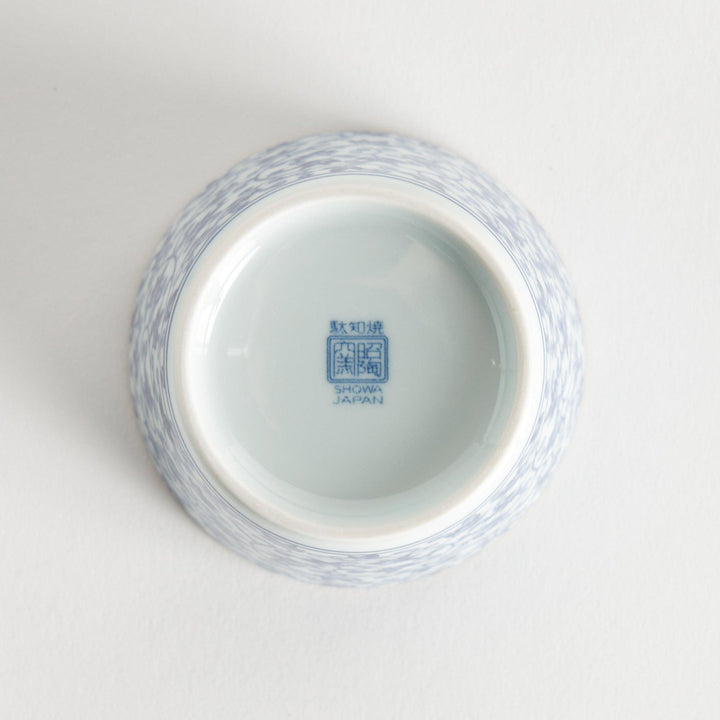 A small, cylindrical cup with an intricate blue floral pattern on a white background.