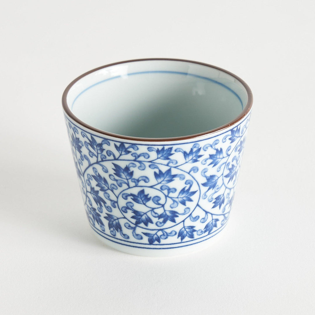 A small, cylindrical cup with an intricate blue floral pattern on a white background.