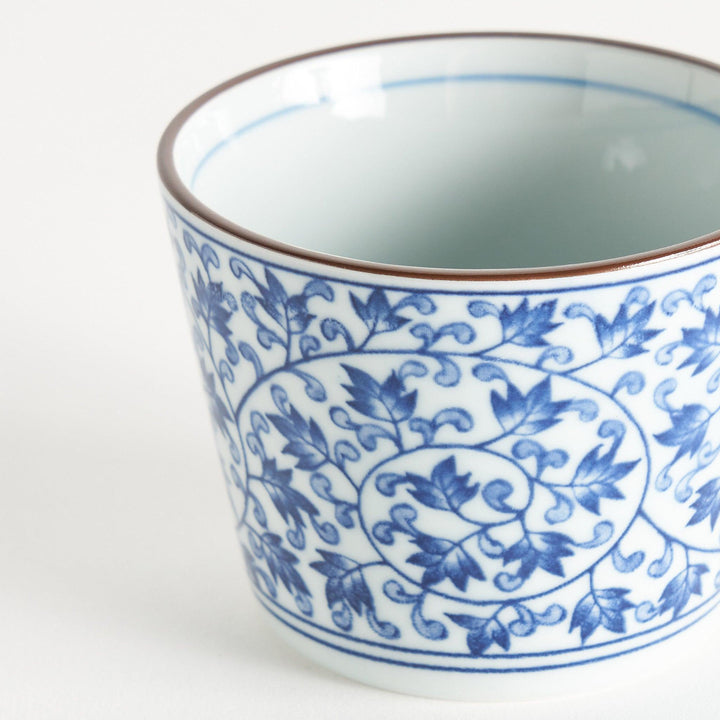 A small, cylindrical cup with an intricate blue floral pattern on a white background.