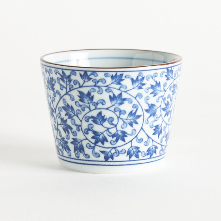 A small, cylindrical cup with an intricate blue floral pattern on a white background.