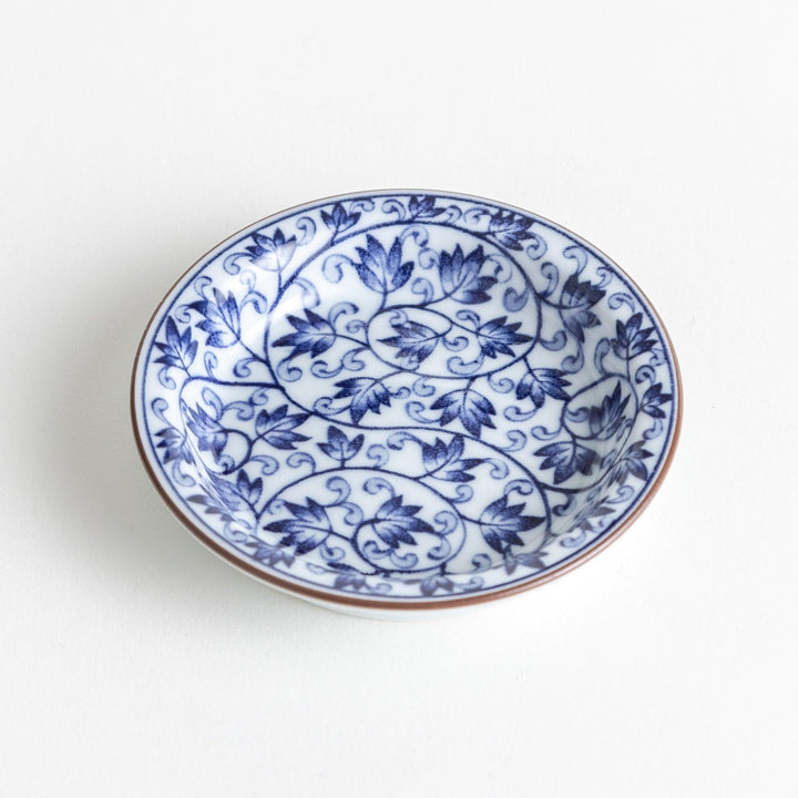 A round dish with a white base and a blue vine pattern swirling around the surface.