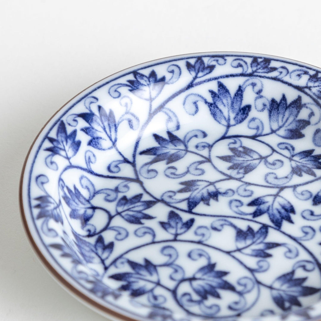 A round dish with a white base and a blue vine pattern swirling around the surface.