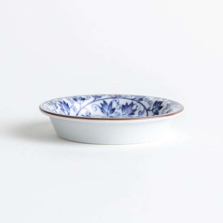 A round dish with a white base and a blue vine pattern swirling around the surface.