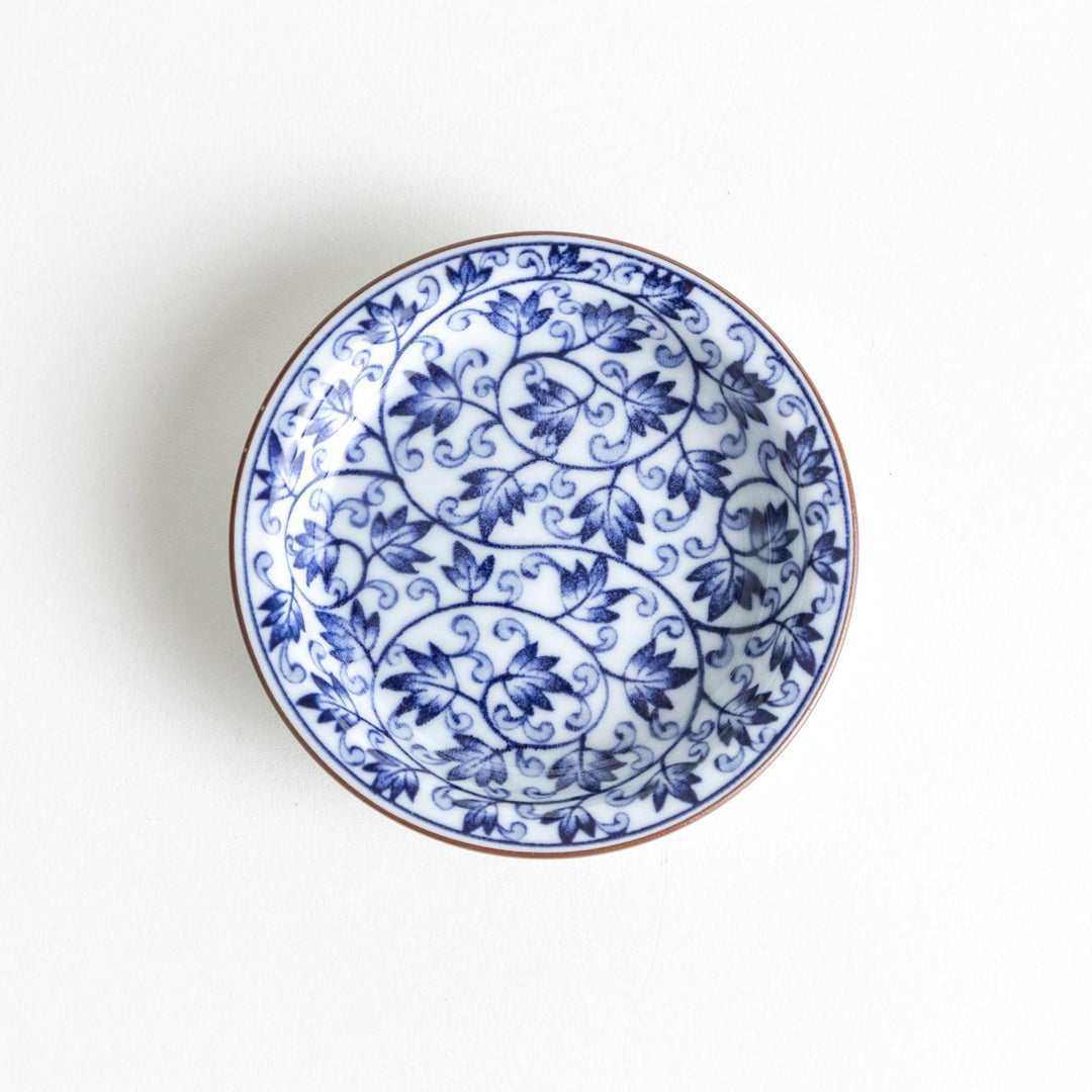 A round dish with a white base and a blue vine pattern swirling around the surface.