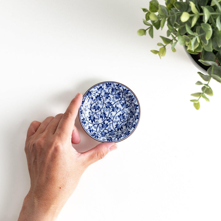 A round dish with a white base and a blue vine pattern swirling around the surface.