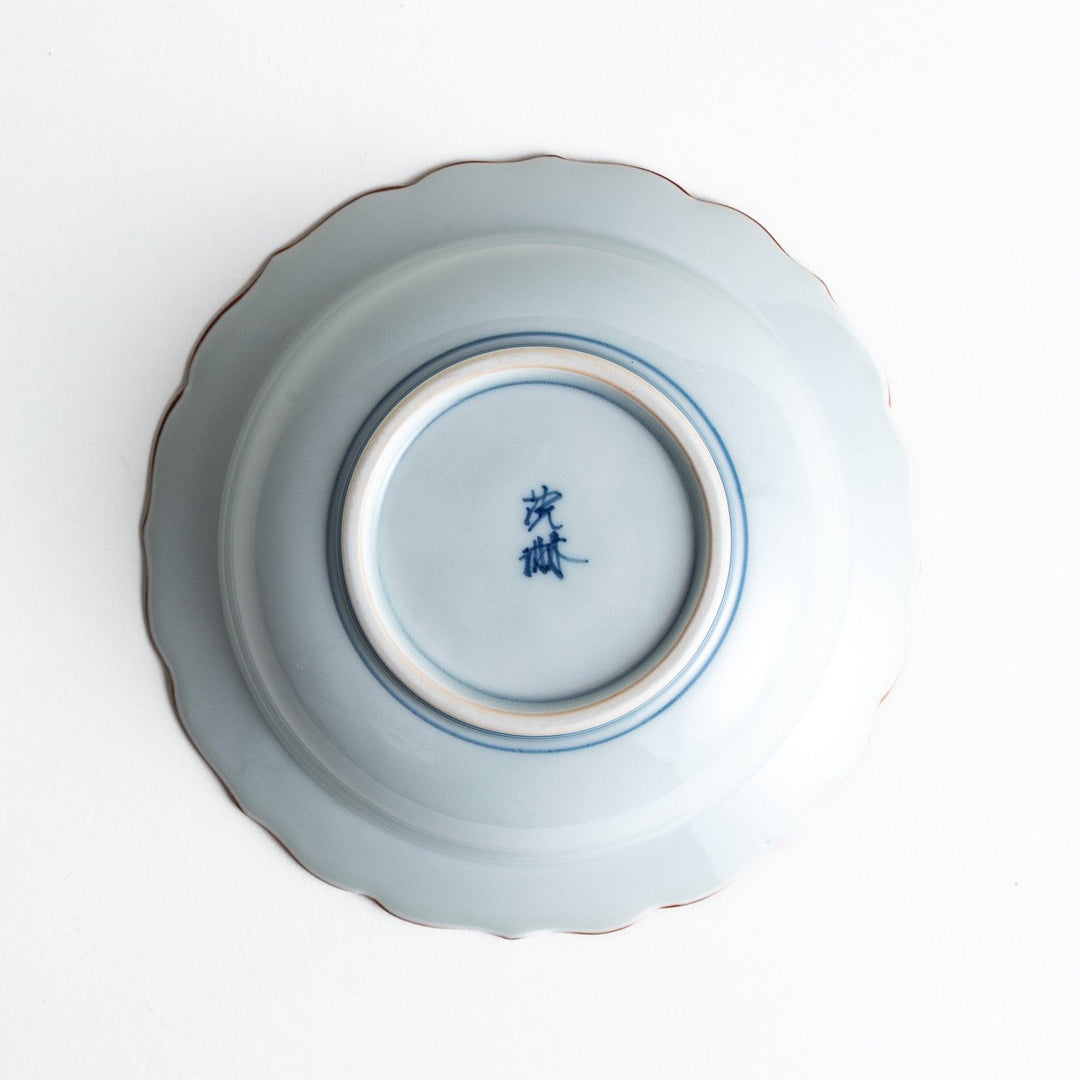 A ceramic bowl featuring a blue arrow feather pattern and scalloped edges.