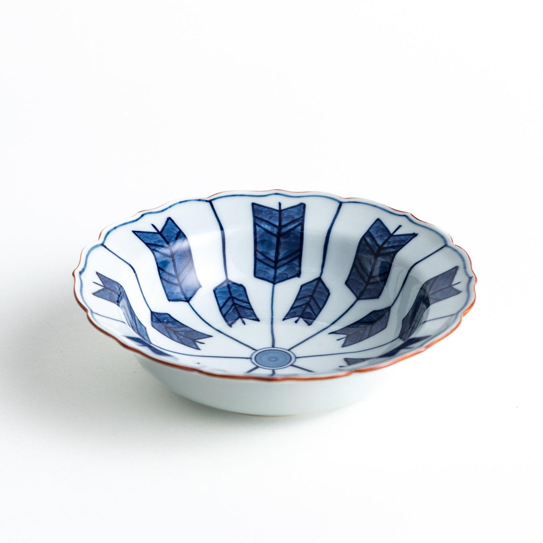 A ceramic bowl featuring a blue arrow feather pattern and scalloped edges.