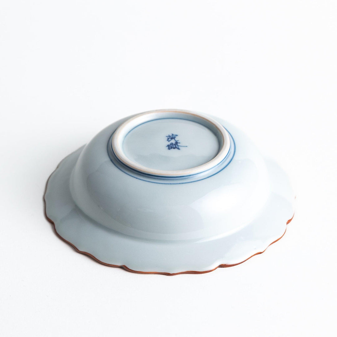 A ceramic bowl featuring a blue arrow feather pattern and scalloped edges.