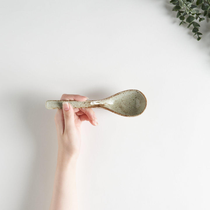 A matching light gray, textured and speckled ceramic spoon.