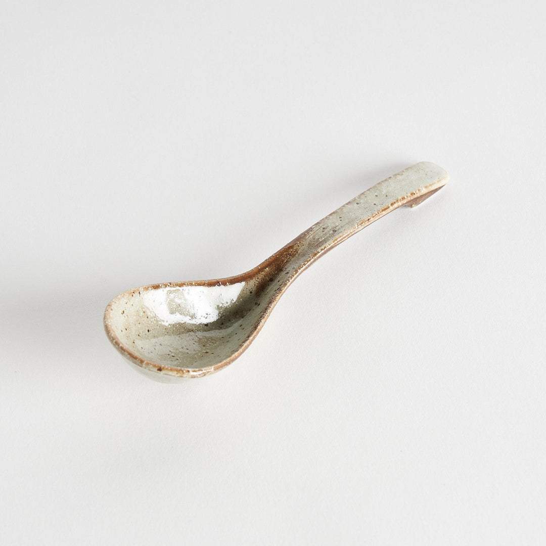 A matching light gray, textured and speckled ceramic spoon.