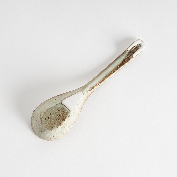 A matching light gray, textured and speckled ceramic spoon.