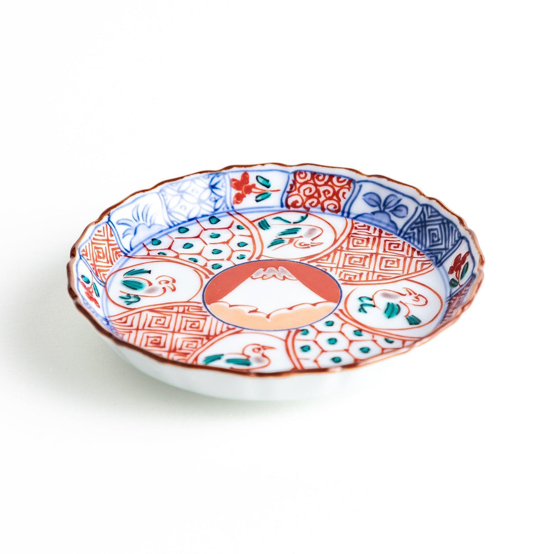 A vibrant ceramic dish with intricate patterns in blue, red, and green, centering around a depiction of Mount Fuji.