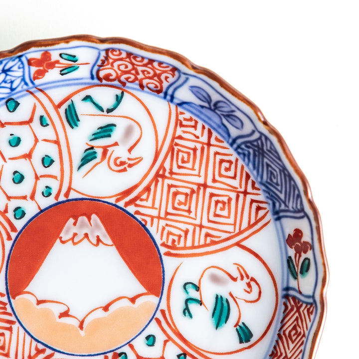 A vibrant ceramic dish with intricate patterns in blue, red, and green, centering around a depiction of Mount Fuji.