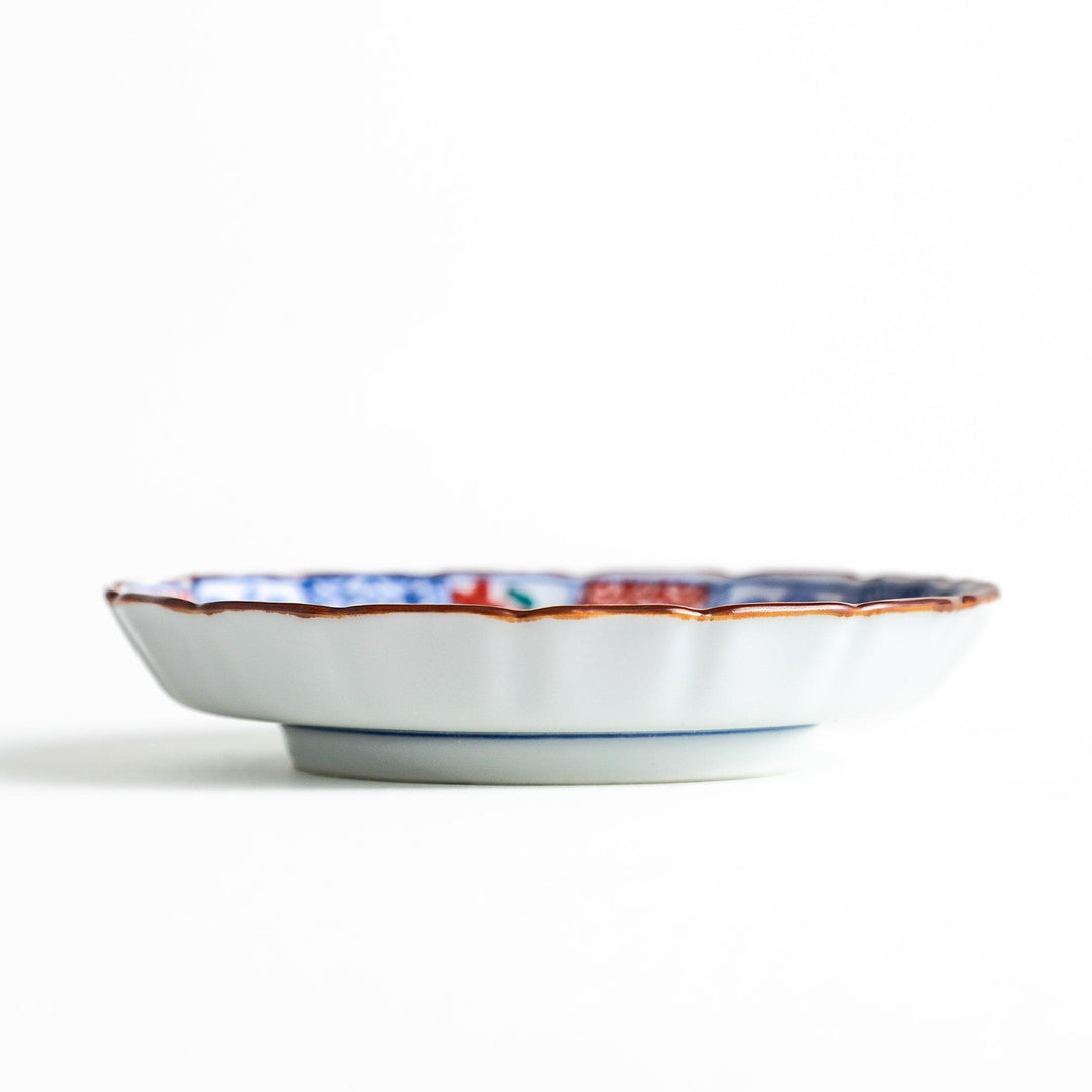 A vibrant ceramic dish with intricate patterns in blue, red, and green, centering around a depiction of Mount Fuji.