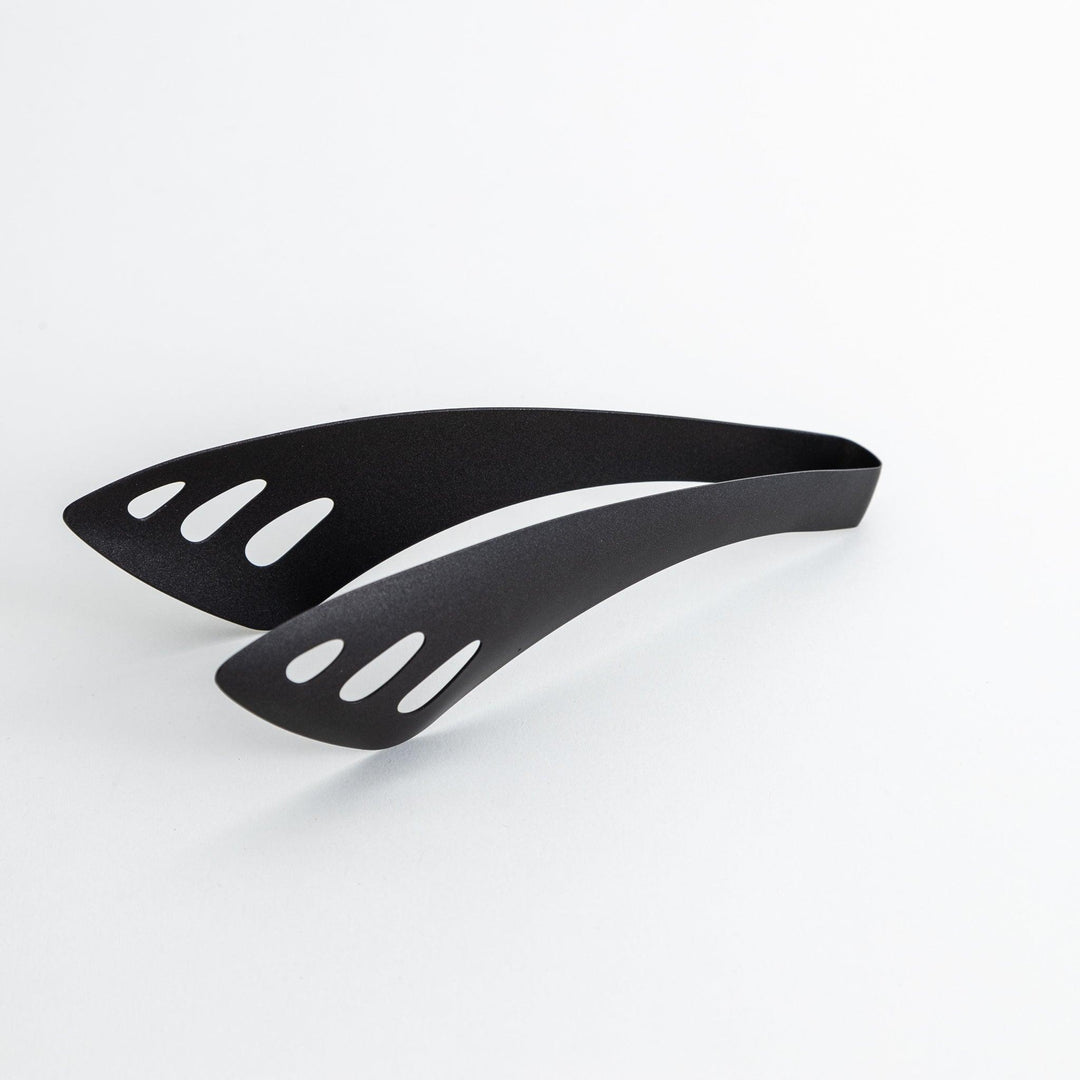 Matte black serving tongs with curved tips and a sturdy design, featuring small holes for draining or straining when serving.