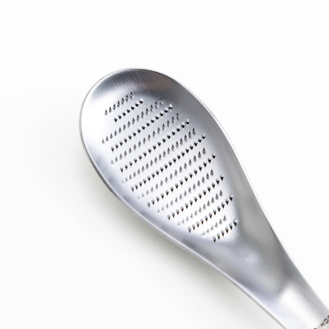 Stainless steel grater with an ergonomic curved handle and fine grating surface, designed for zesting and grating.