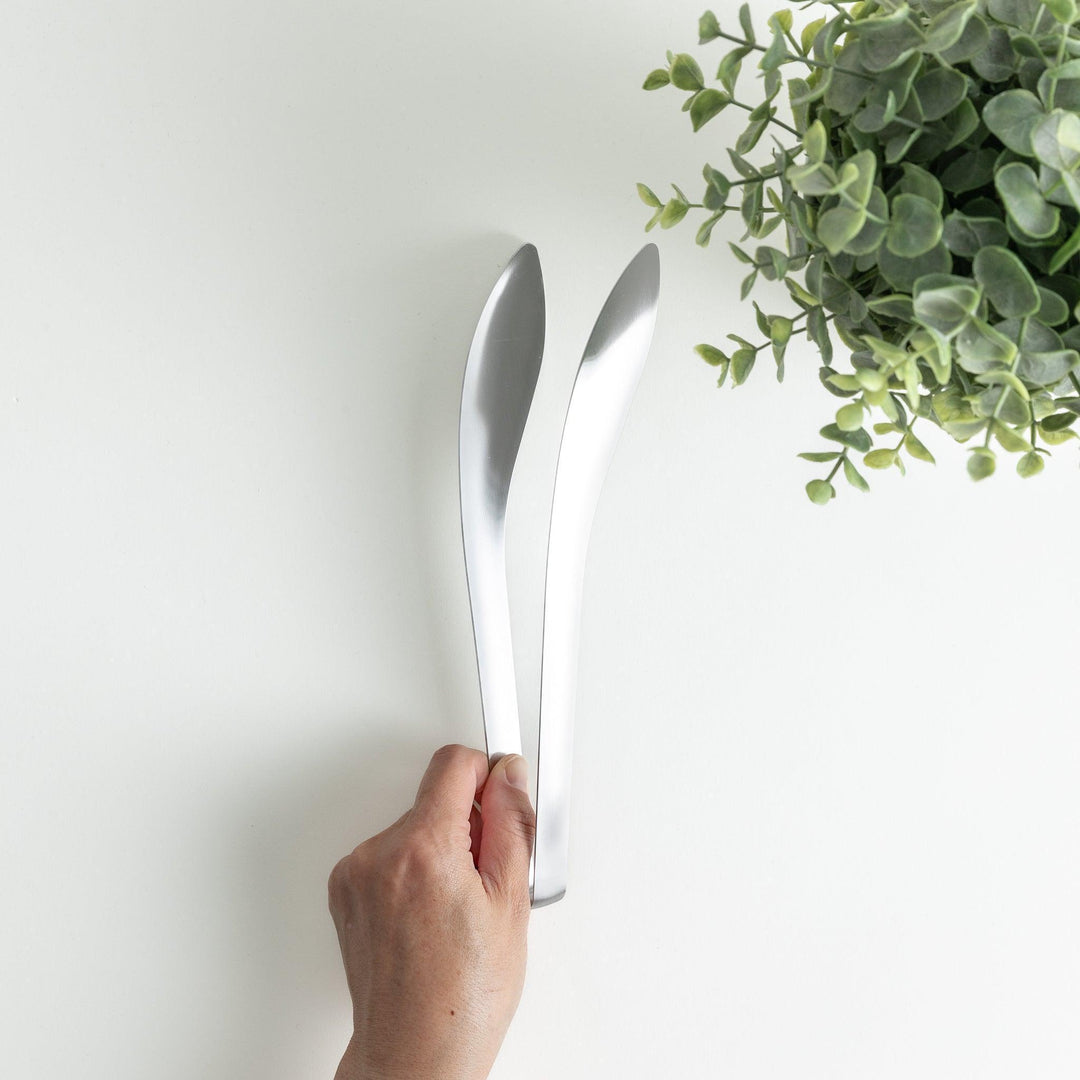 Smooth, curved stainless steel tongs with a minimalist design.