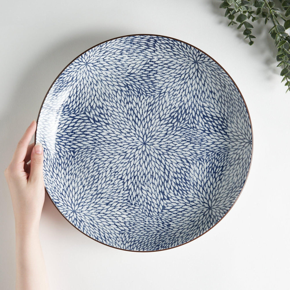 A round serving plate adorned with a detailed pattern of concentric blue dots creating a mesmerizing effect.