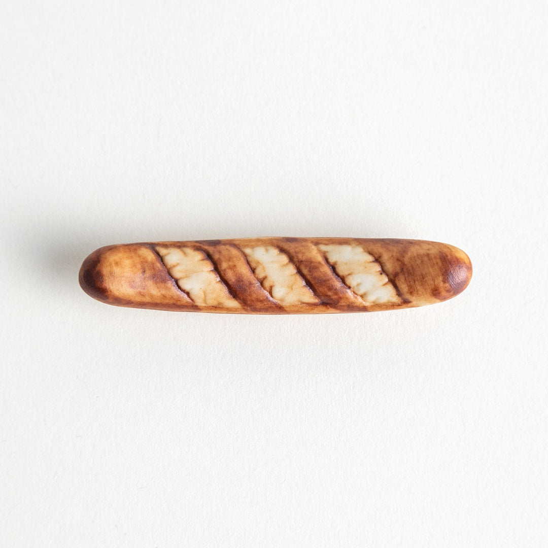 A ceramic chopstick rest designed to resemble a miniature baguette.\