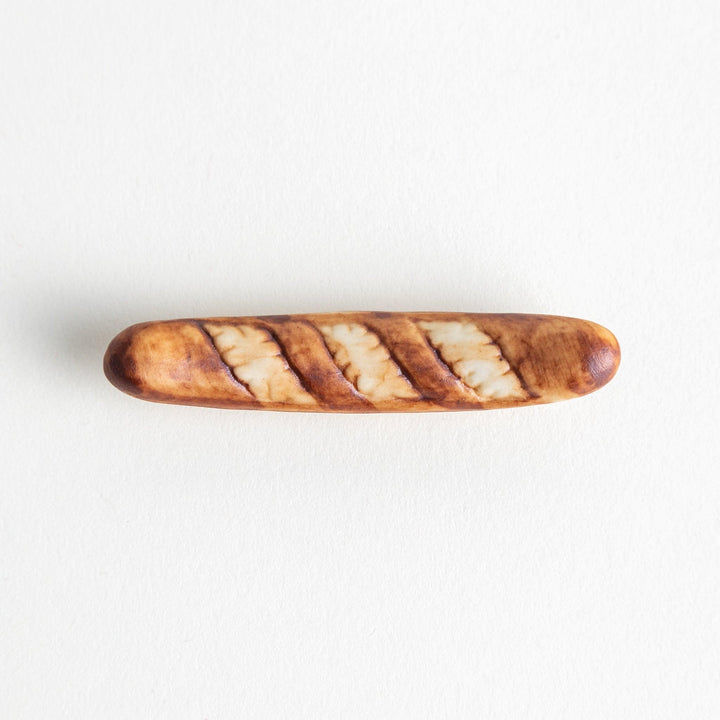 A ceramic chopstick rest designed to resemble a miniature baguette.\